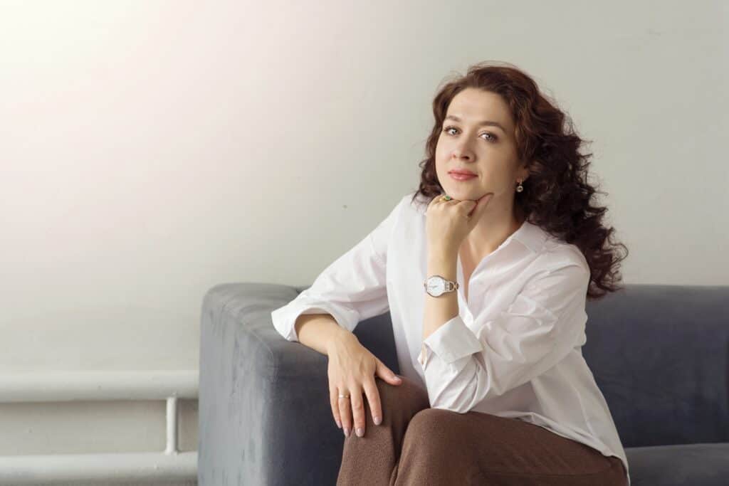 a,young,beautiful,woman,sits,on,a,gray,sofa,and